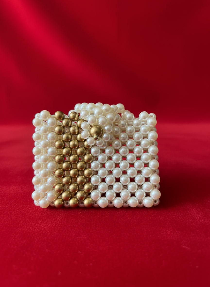 Small handbag made of white and gold beads on a red background