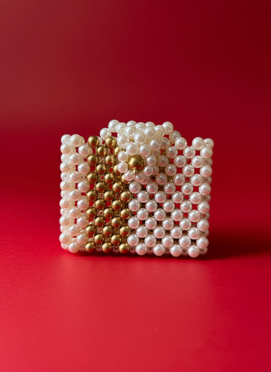 Small handbag made of pearls and gold beads on a wooden surface