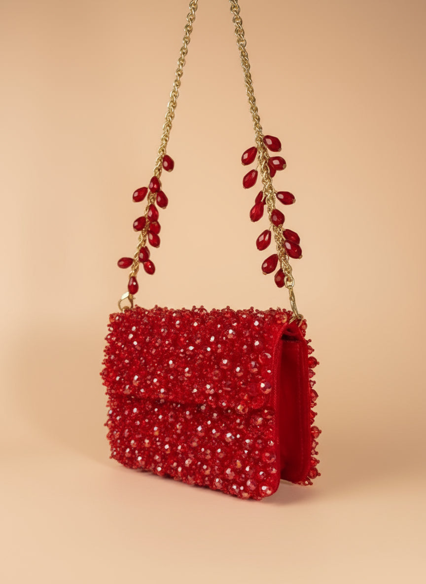 Red beaded handbag with gold chain on a white background