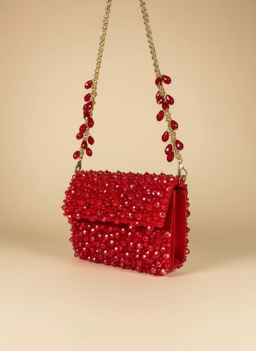 Red beaded handbag with gold chain on a white background clutch saree clutch