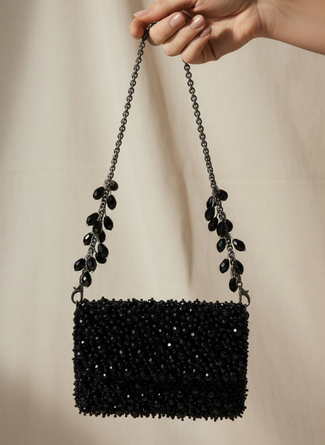Black beaded handbag with chain strap on a white background